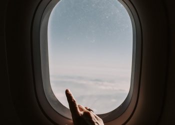 person pointing to the sky from an airplane window