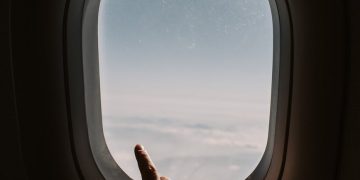 person pointing to the sky from an airplane window