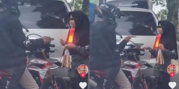 Pengendara motor membeli kacang di lampu merah.